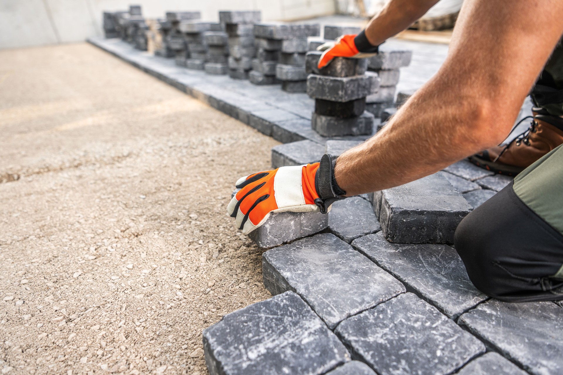 Worker Laying Paving Stones for Pathway Construction at Construction Site